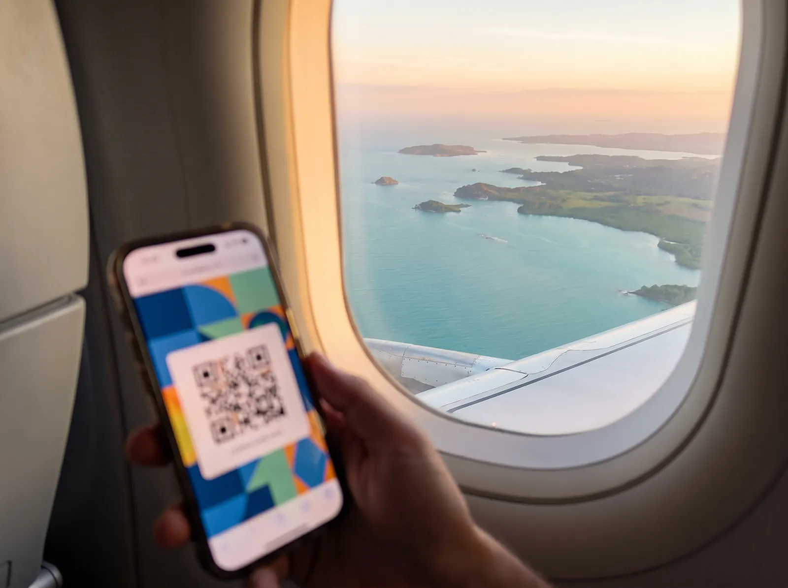 Pase de abordar en el celular junto a la ventanilla de un avión sobre el Caribe