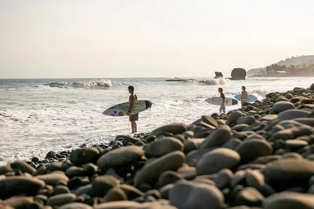 Surfistas en la playa de piedras de El Tunco